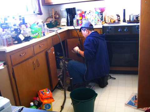 A plumber clearing a drain; image courtesy Rick